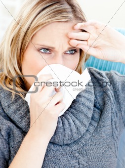 Dejected woman using a tissue sitting on a sofa