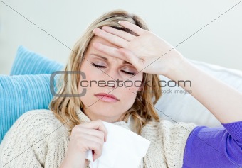 Sick woman with headache lying on the sofa in the living-room