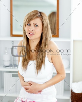 Blond woman having a stomachache in her bathroom
