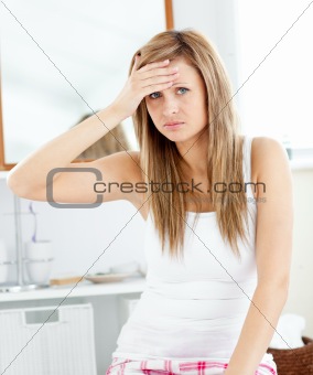 Depressed woman with a headache looking at the camera in the bat