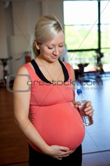 Pregnant woman relaxing while holding water bottle.