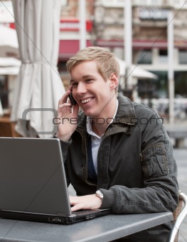 Young happy man with phone and laptop