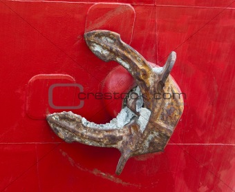 Old heavy rusty anchor on a red freighter's hull