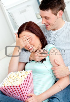 Charming couple lying on the sofa with popcorn and remote