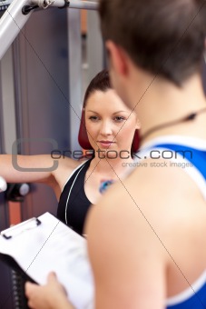 Assertive athletic woman using a bench press with her coach
