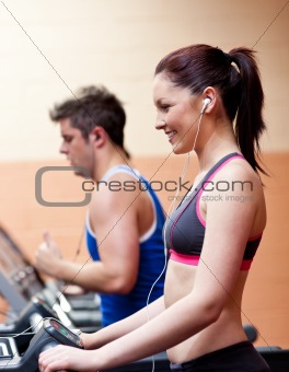 Young athletes exercising on a running machine with earphones