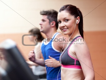 Young beautiful athletes with earphones exercising on a running 