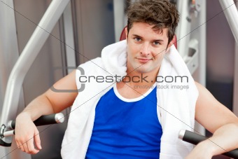 Confident young man with a towel using a bench press