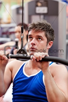 Muscular male athlete practicing body-building in a fitness center