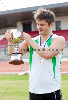 Athletic man holding a trophee in a middle of the stadium