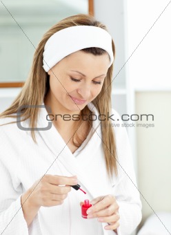 Bright caucasian woman varnishing her fingernails in the bathroo