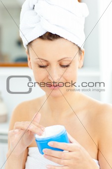 Caucasian young woman putting moisturizer on her face in the bat