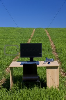Desk and Computer In Green Field With Path