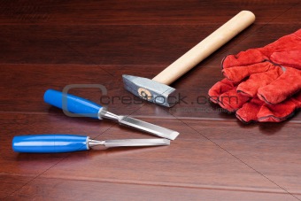 Red gloves, hammer and blue chisels on dark background