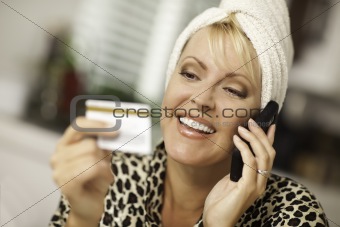 Robed Woman on Cell Phone Looking At Her Credit Card.