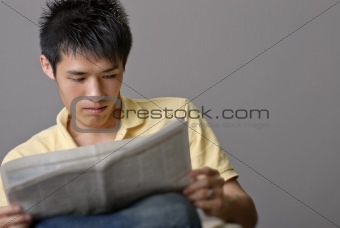 Asian young man reading newspaper