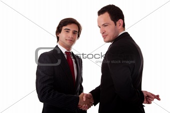 two businessmen shaking hands, and one businessman with his fingers crossed behind his back and smiling