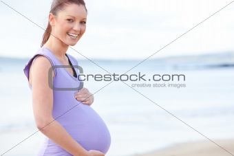 Smiling pregnant woman standing on the beach