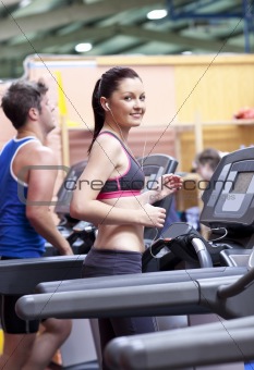 Athletic woman listening to the music while using a treadmill in