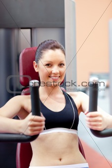 beautiful athletic woman using a bench press smiling at the came