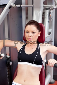 concentrated athletic woman using a bench press in a fitness cen