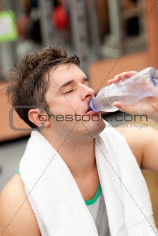 exhausted man drinking water with towel around the neck after a 