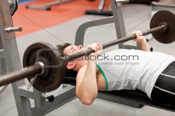 muscular young man using weightlifting lying in a fitness centre