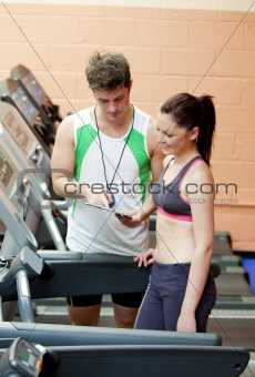 Happy woman listening to her coach after doing exercises on a tr