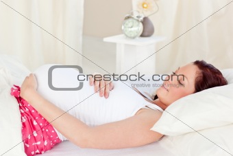 Radiant pregnant woman resting n her bed in the bedroom