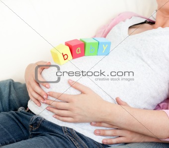 Close-up of a pregnant woman with baby cubes on her belly and of