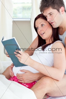 Close-up of a shocked pregnant woman and her husband reading a b