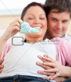 Portrait of a bright pregnant woman holding baby shoes and of he