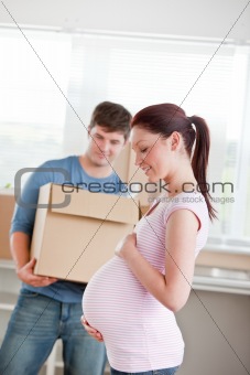 adorable future mother with husband standing in their new house 
