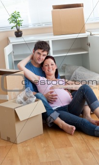 Future parents sitting on the floor surrounded by boxes