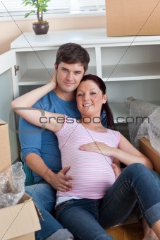 happy couple in their new home sitting on the floor among cardbo