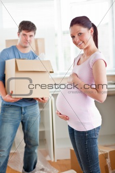 adorable pregnant woman with husband holding cardboard