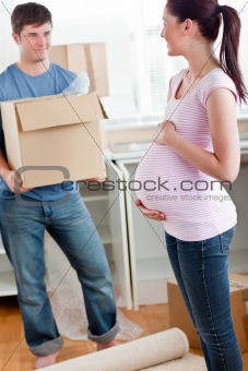 cute pregnant wife looking at her husband holding box standing i