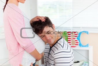 careful young man listening to the belly of his pregnant wife