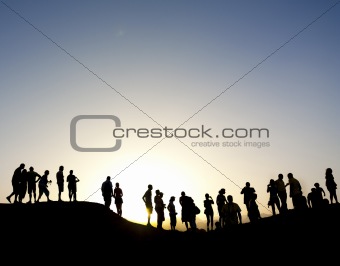 Group of people silhouetted against the sun on top of a mountain