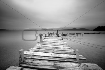 Looking over a pier and boats, black and white