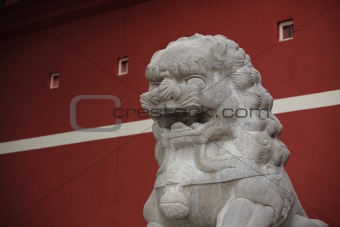 stone lion statue before the red wall