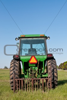 Green Tractor in a Farm Field with Blue Sky