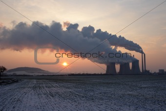 View of coal powerplant against sun and huge fumes