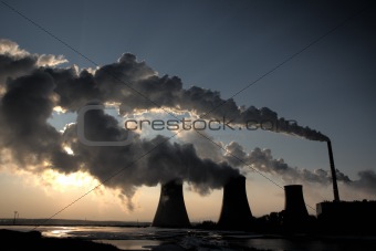 View of coal powerplant against sun and huge fumes