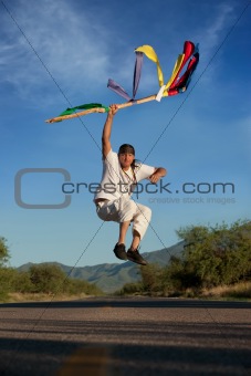 Man jumping in the middle of a road with colorful flags