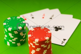 Casino chips and four aces against green background