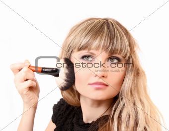 beautiful young woman applying makeup with brush
