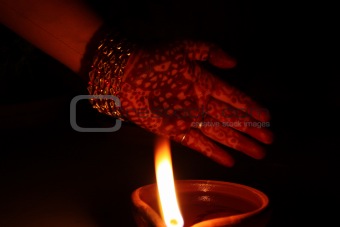 Hand with Mehndi (henna) in front of a lamp