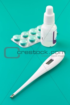 Thermometer, pills and nasal drops closeup