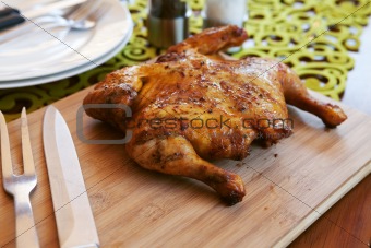 Whole cooked chicken with cutlery and spices